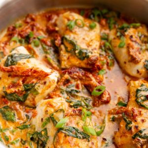 Large stainless steel skillet full of sun-dried tomato cod.