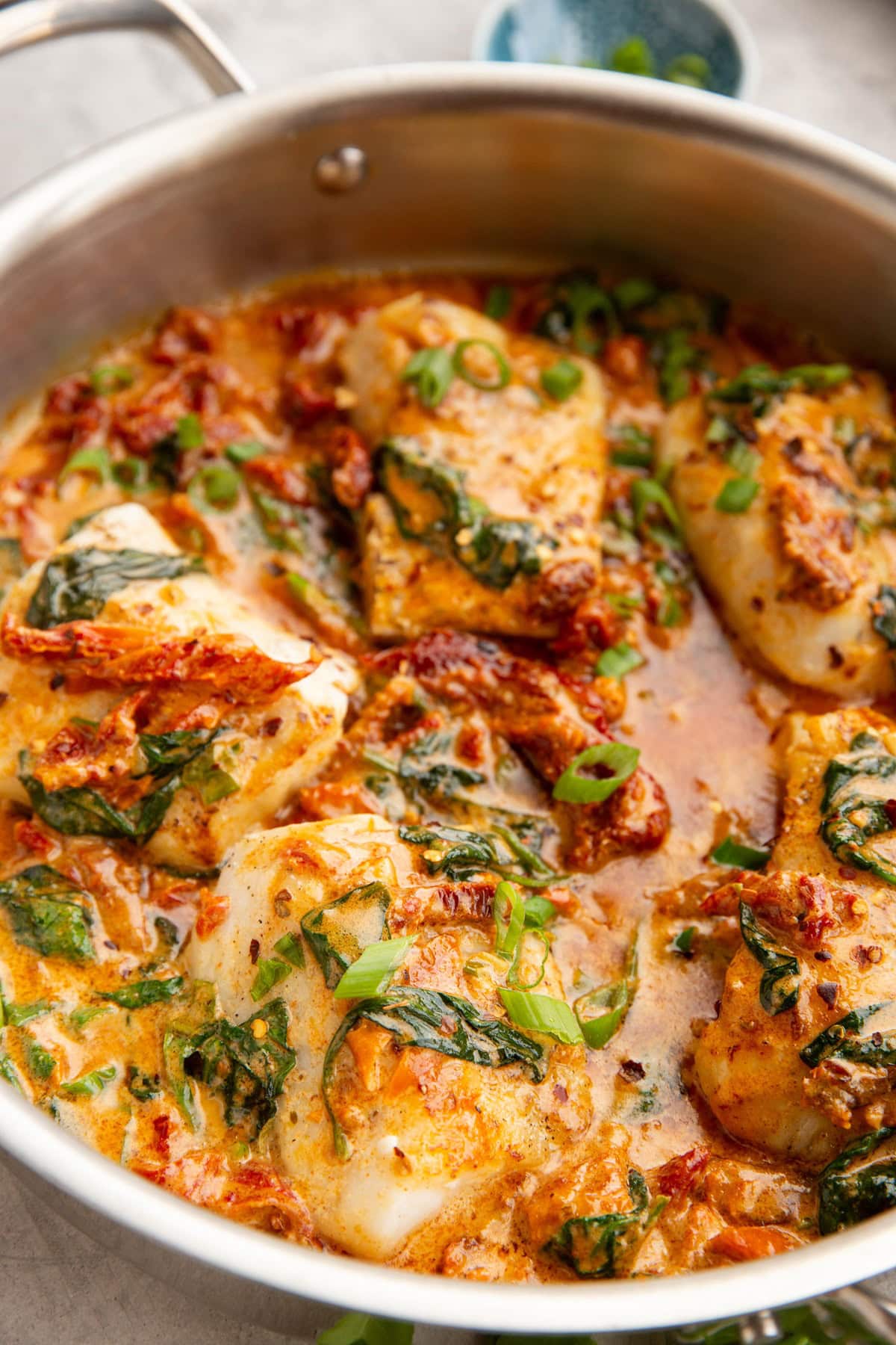 Large stainless steel skillet full of sun-dried tomato cod.