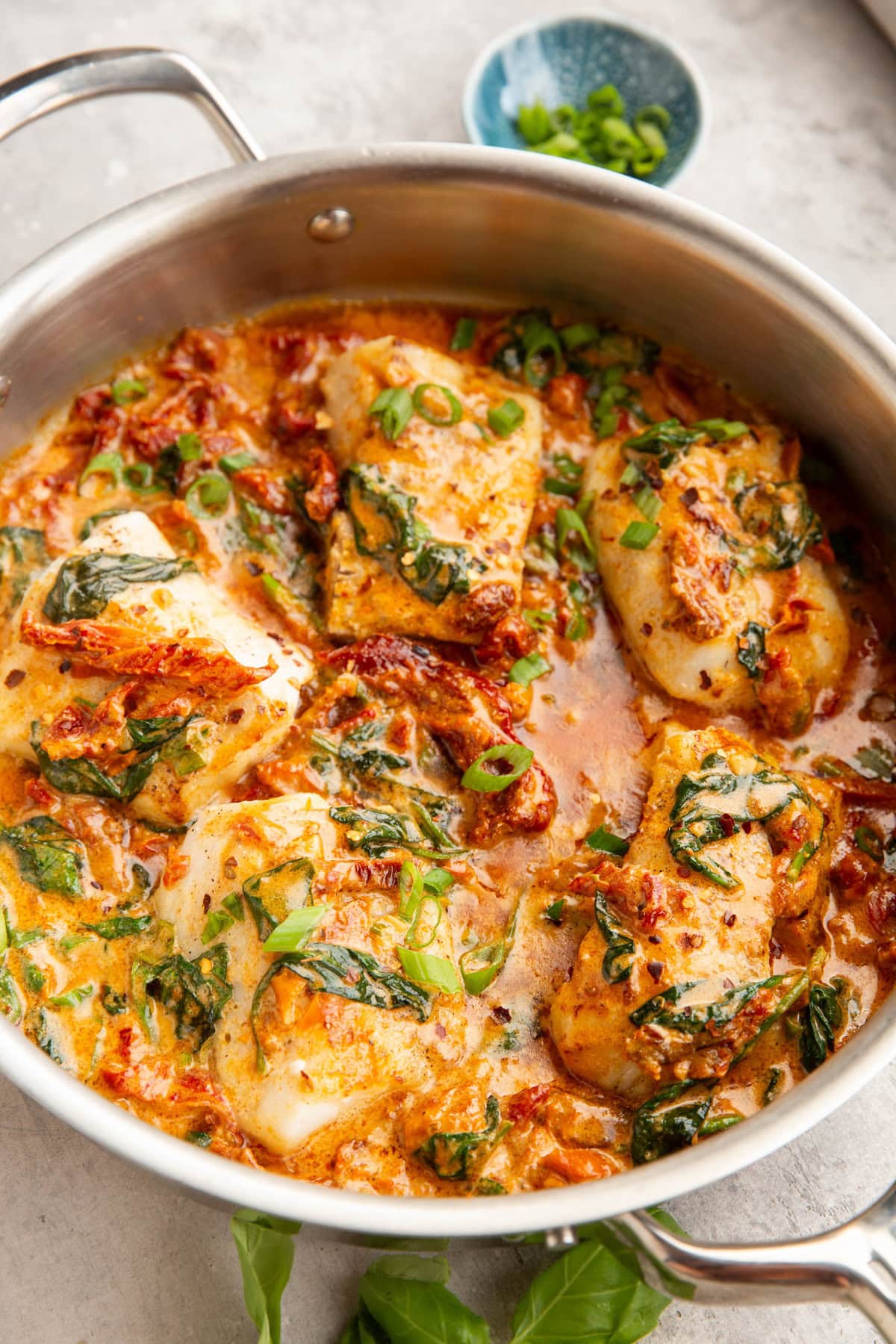 Skillet with sun-dried tomato sauce covered in cod.