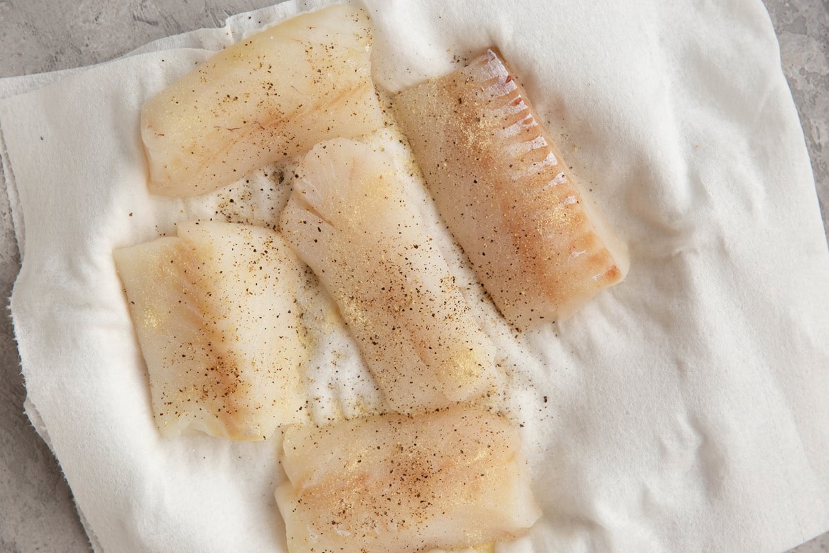 Plate of cod fillets sprinkled with seasonings.