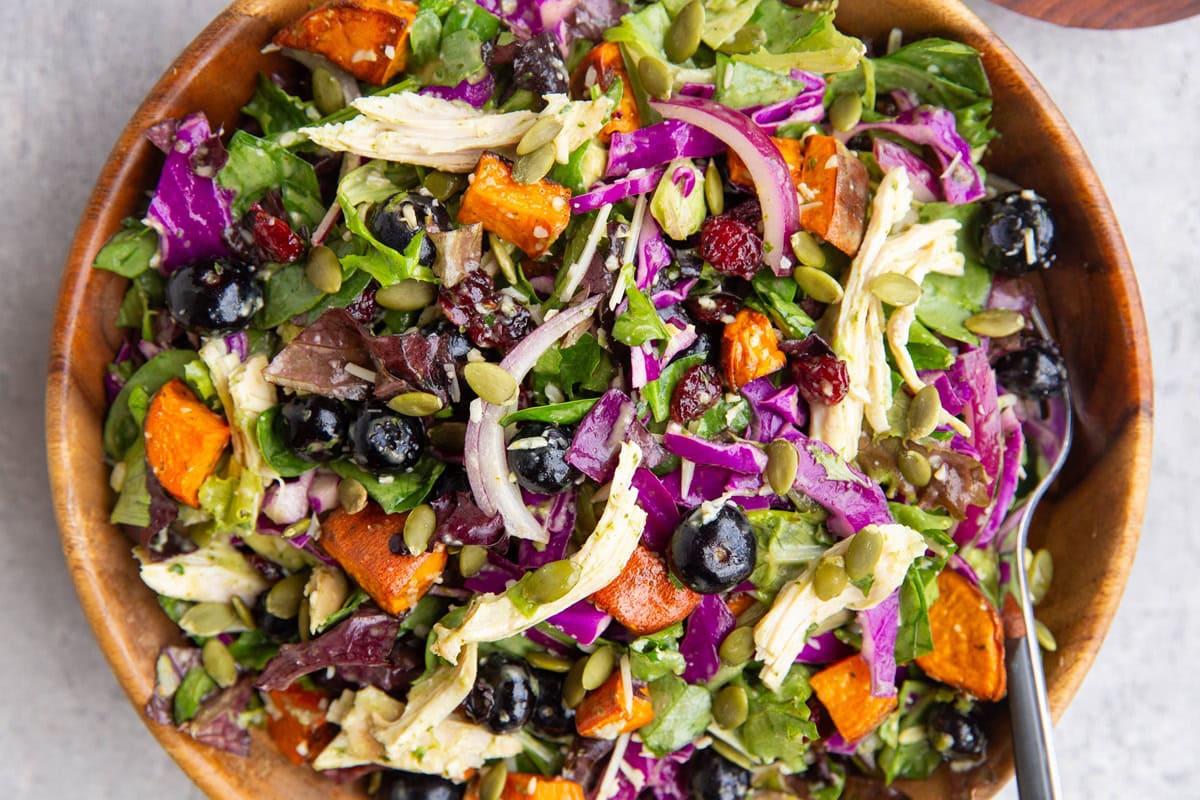 A large wooden bowl of salad with a fork for serving.