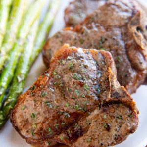 Three bone-in lamb chops on a white plate, ready to serve.