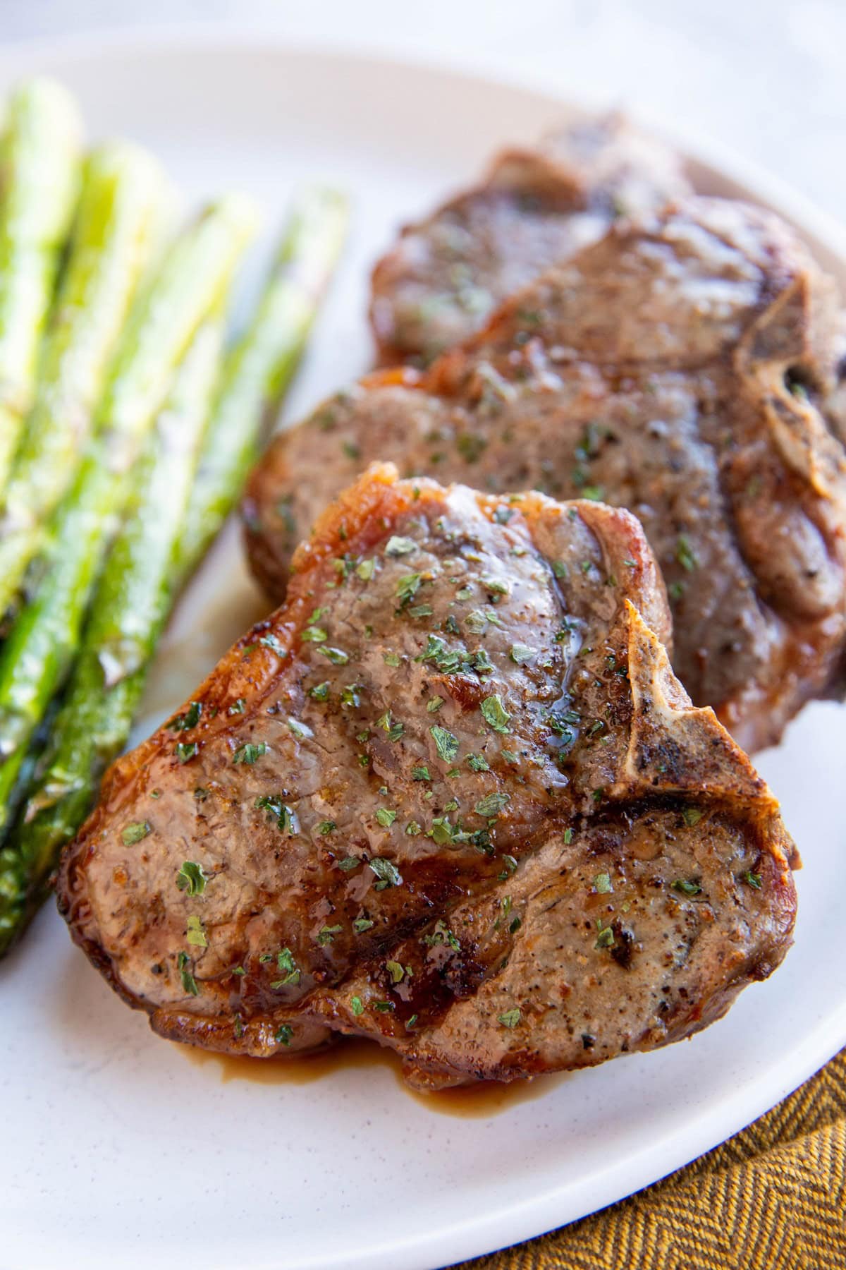 Three bone-in lamb chops on a white plate, ready to serve.