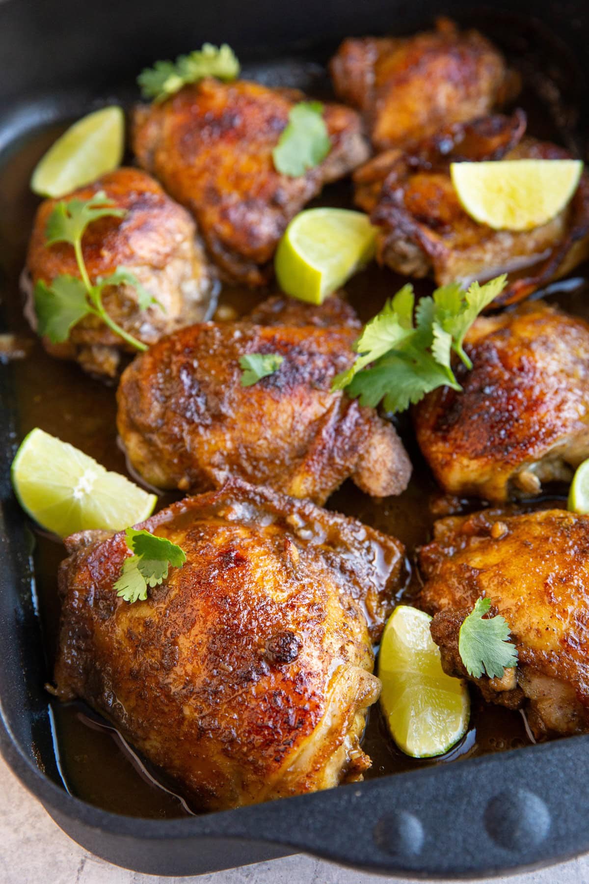 Baked Jamaican Jerk chicken in a large casserole dish with lime slices and fresh cilantro, ready to serve.