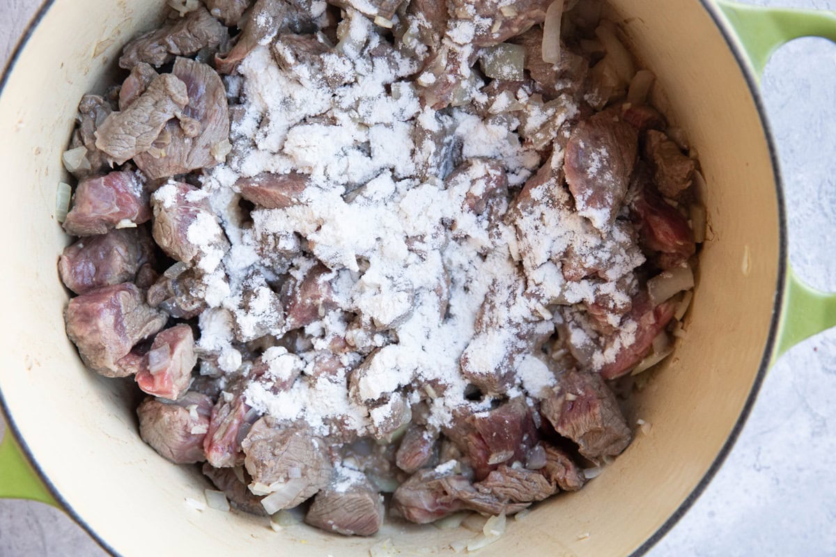 Pot of browned beef with flour sprinkled on top.