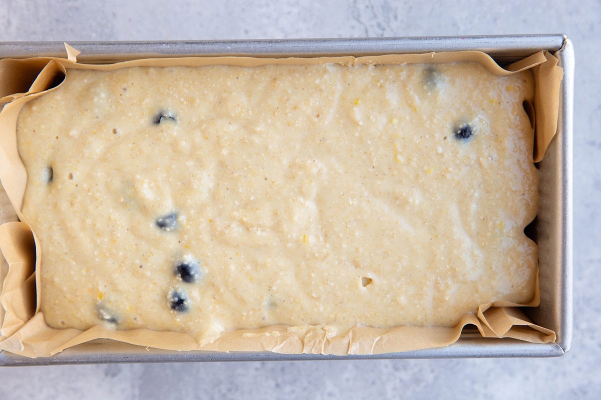 Loaf pan with lemon blueberry bread batter inside, ready to bake.