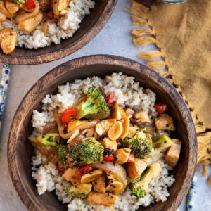 Two wooden bowls of chicken and broccoli stir fry.