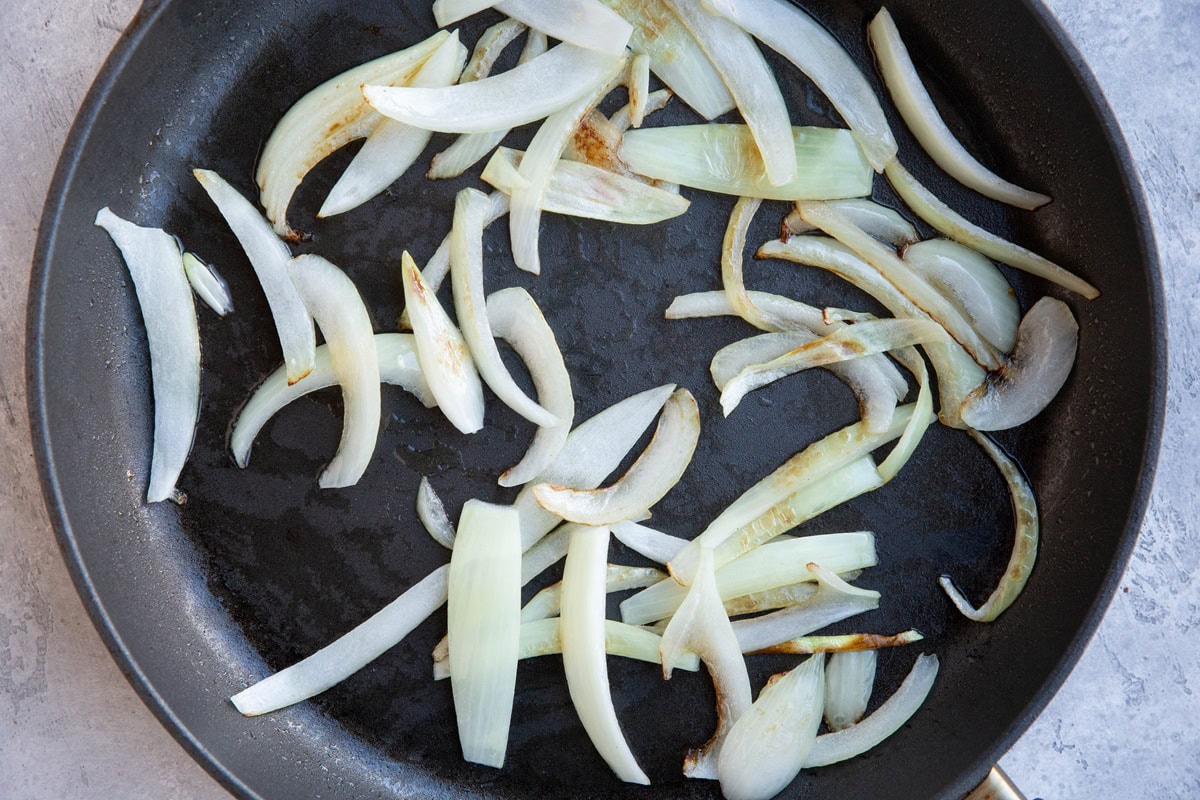 Sliced onions cooking in a skillet.