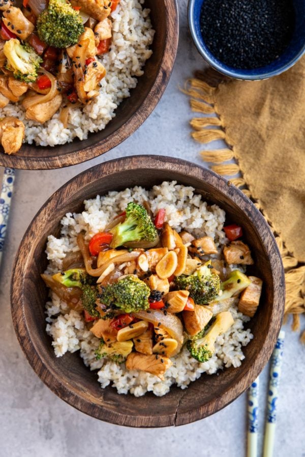 Two wooden bowls of chicken and broccoli stir fry.