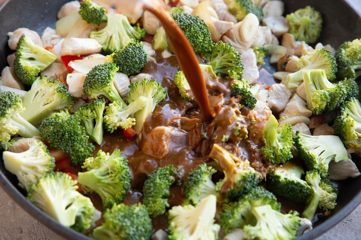 Pouring the stir fry sauce into the skillet with the rest of the ingredients.