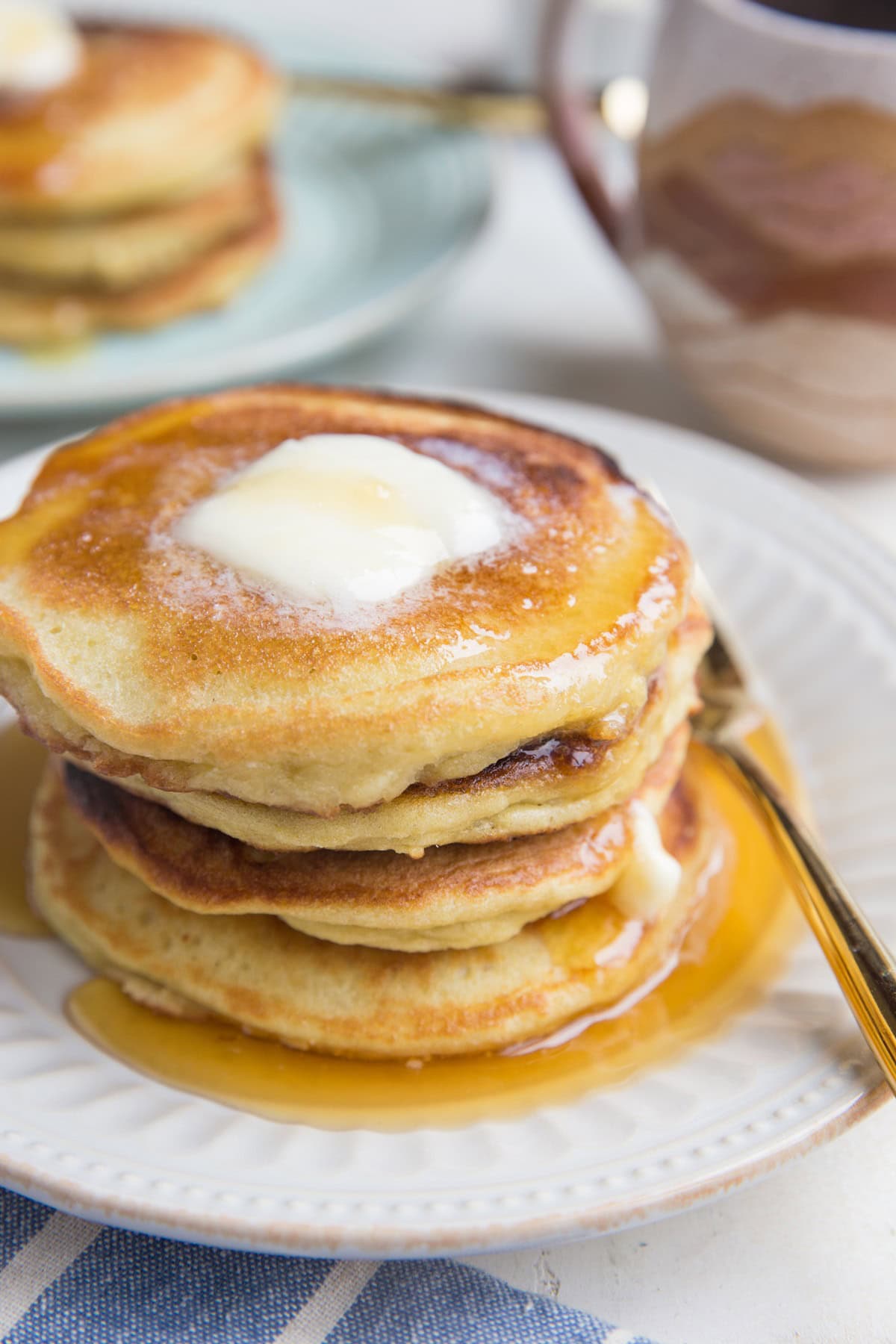 Stack of coconut flour pancakes on a plate with melted butter on top, ready to eat.