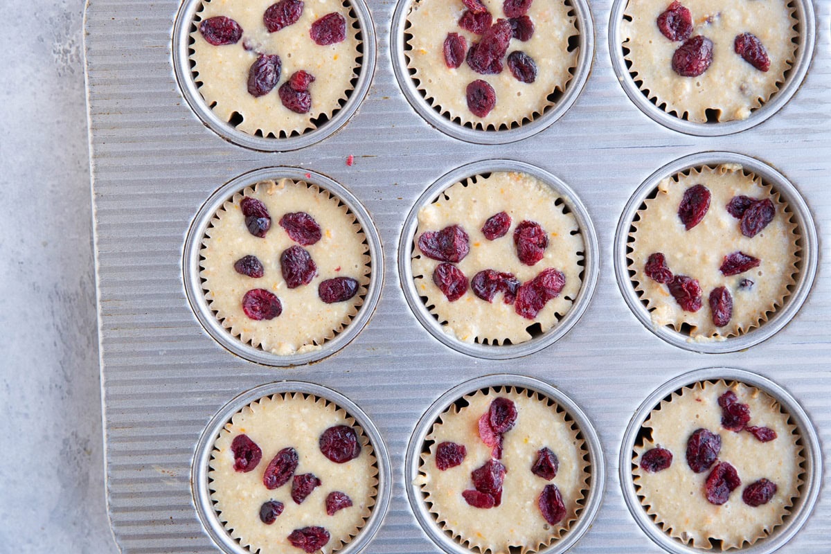 Muffin tin full of cranberry orange muffin batter.