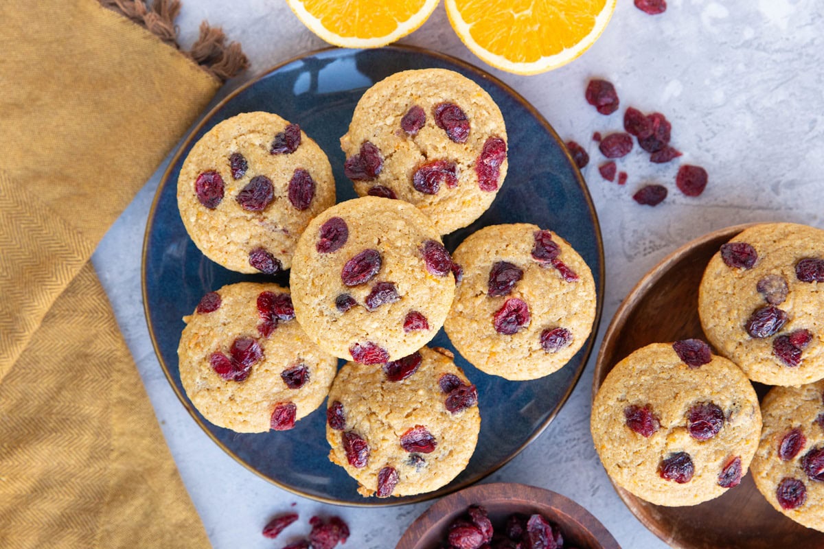 Two plates with cranberry orange muffins on top, ready to serve.