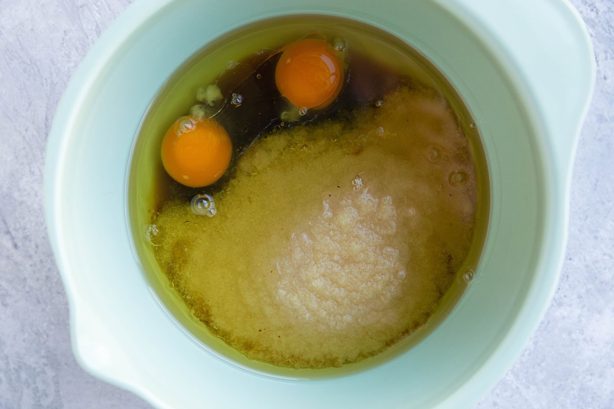 Mixing bowl with applesauce, maple syrup, eggs, and avocado oil.