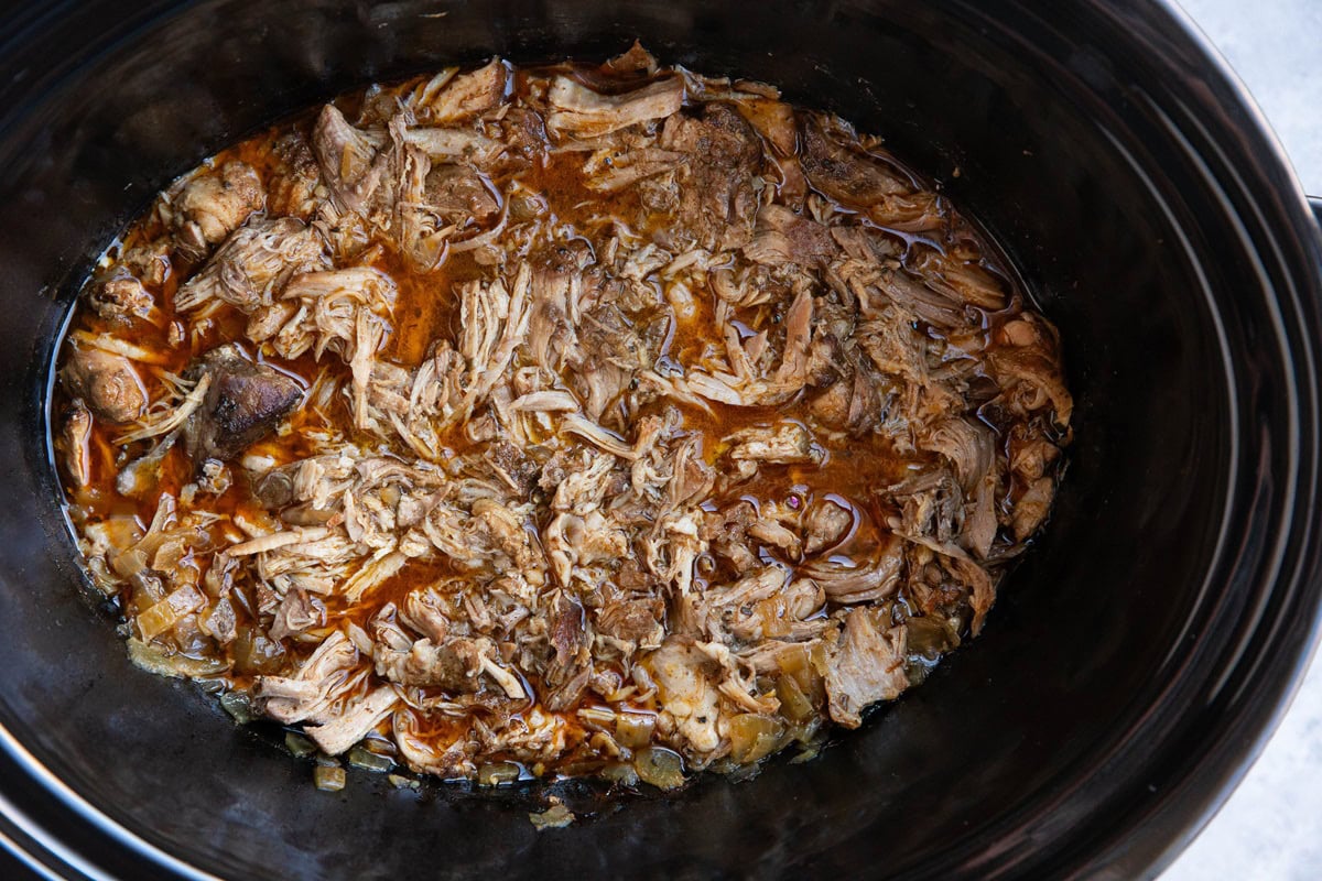 Slow cooker full of shredded pork and juices.