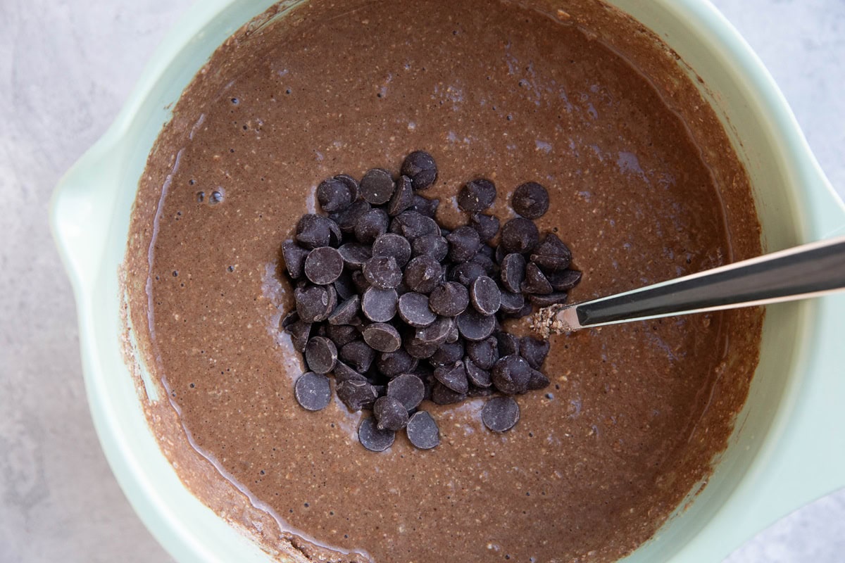 Muffin batter with chocolate chips on top, ready to be stirred in.