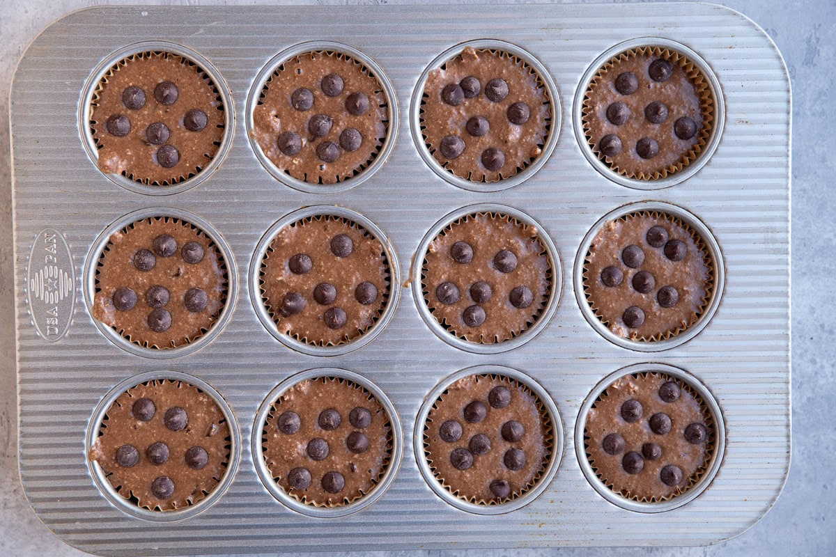 Healthy chocolate oatmeal muffin batter in a muffin tin, ready to go into the oven.