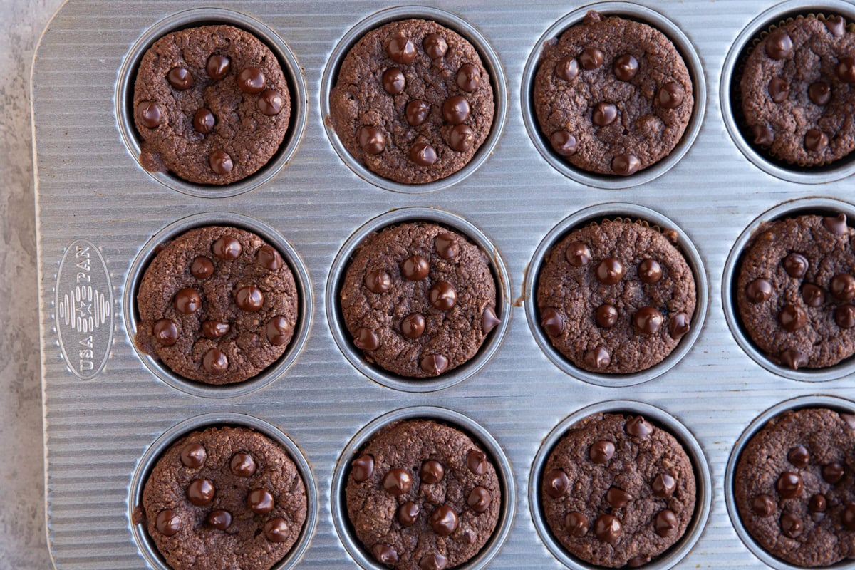 Muffin tin full of chocolate muffins, fresh out of the oven.