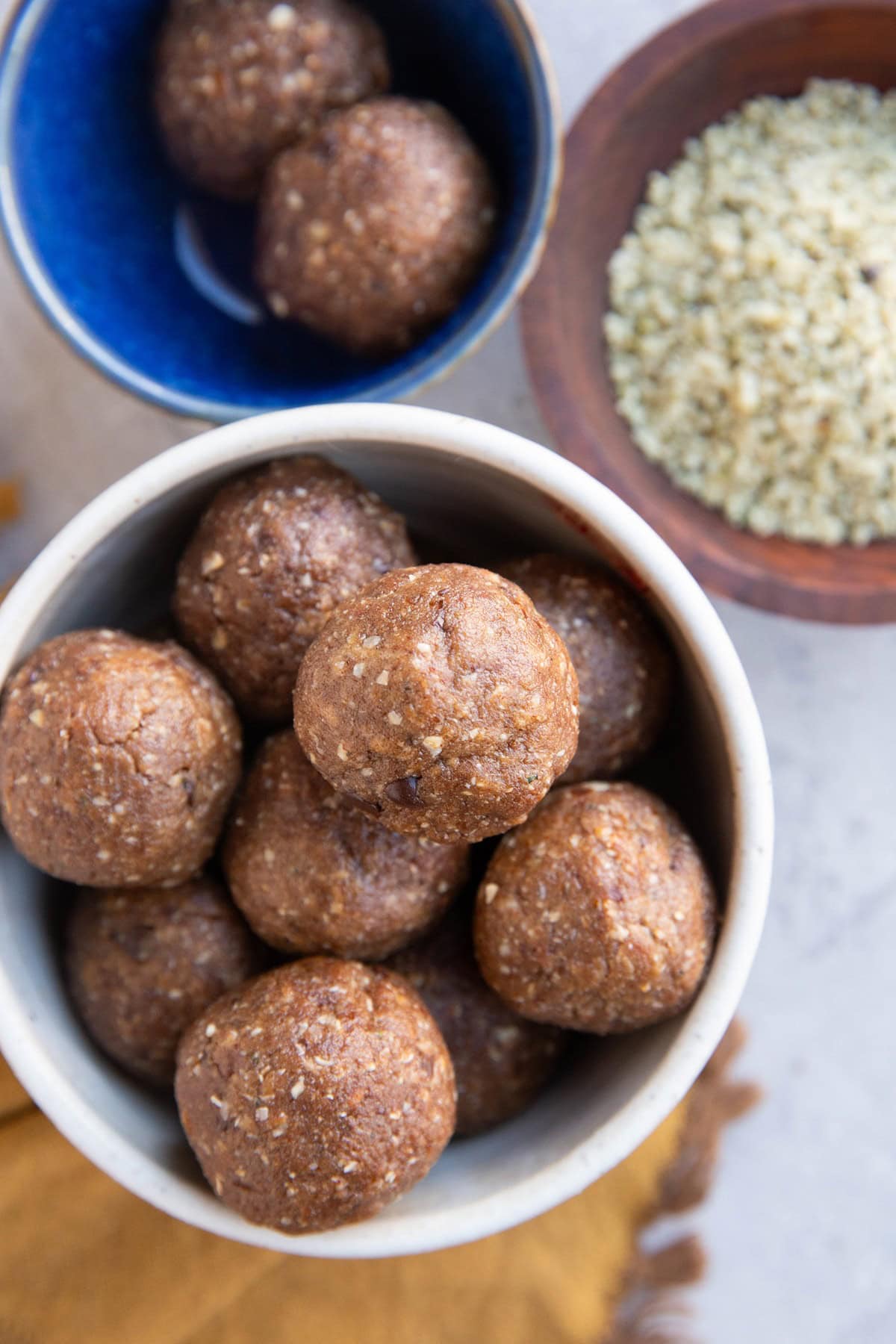 Bowl of power balls and a small bowl of two power bowls and a small bowl of hemp seeds.