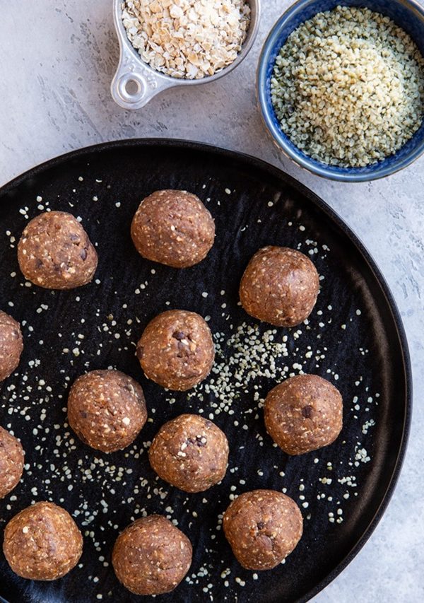 Plate of power balls with hemp seeds and oats to the side.