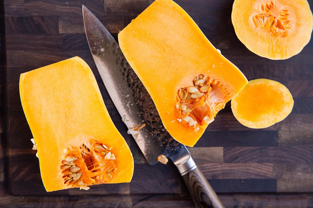 Butternut squash cut in half on a cutting board, exposing the inside.