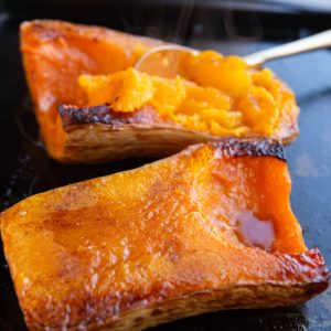 Butternut squash halves cut side up on a baking sheet, fresh out of the oven.