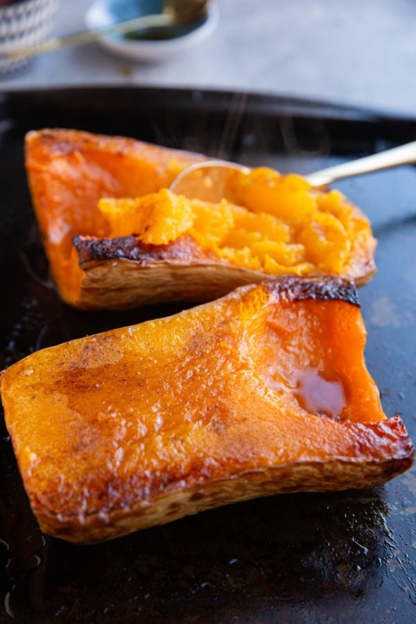 Butternut squash halves cut side up on a baking sheet, fresh out of the oven.