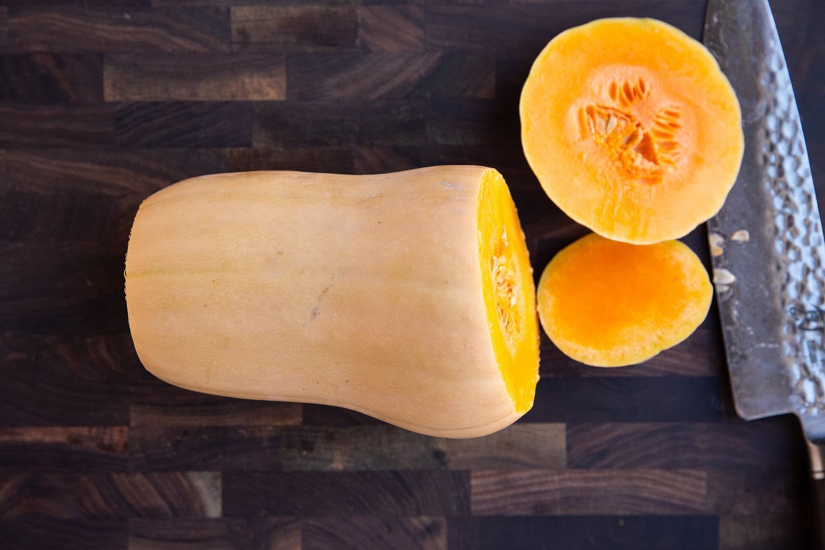 Butternut squash on its side on a cutting board with the tip and tail cut off.