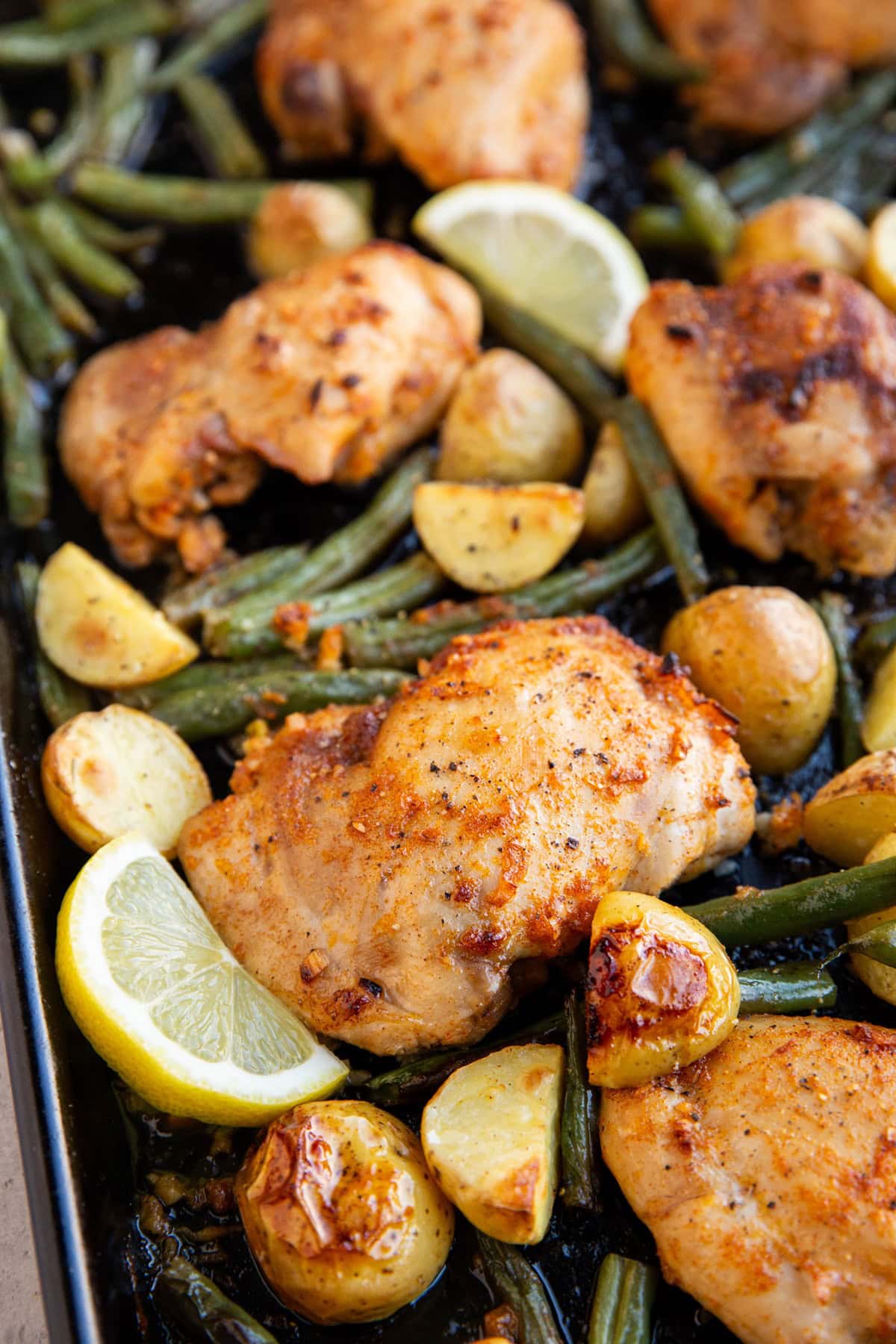 Baking sheet full of lemon chicken and vegetables.