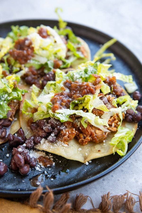 Tostada with shredded chicken and beans on a plate.