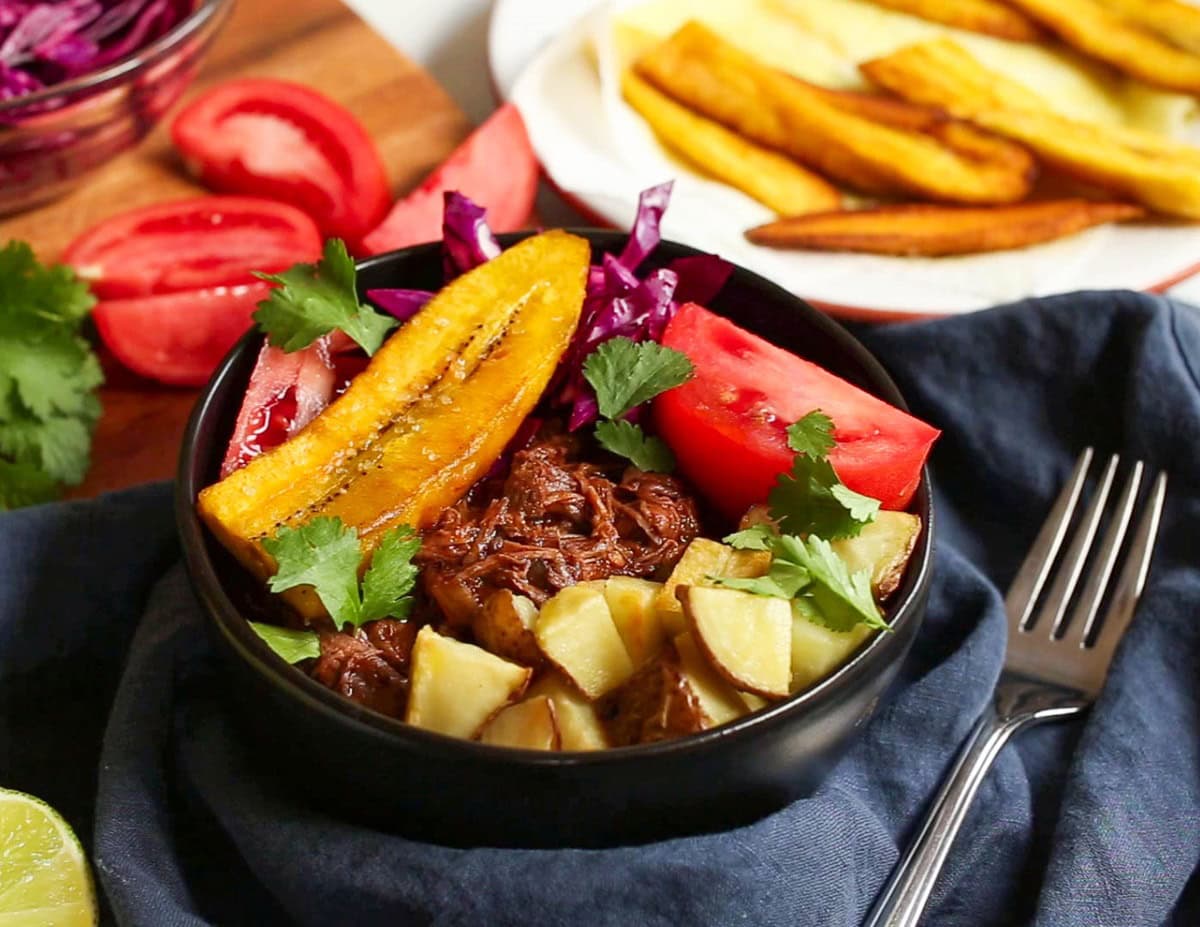 Bowl full of shredded beef, roasted potatoes, and plantains.