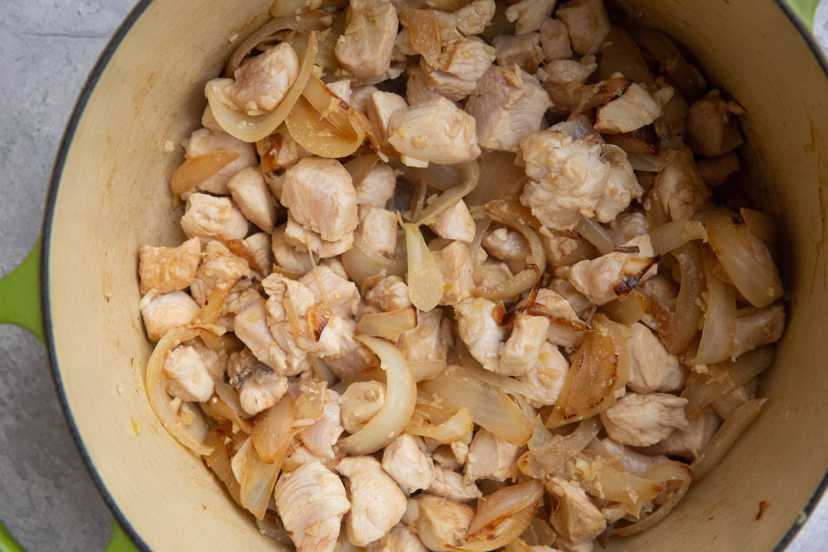 large pot of onions, garlic, ginger, and chicken cooking.