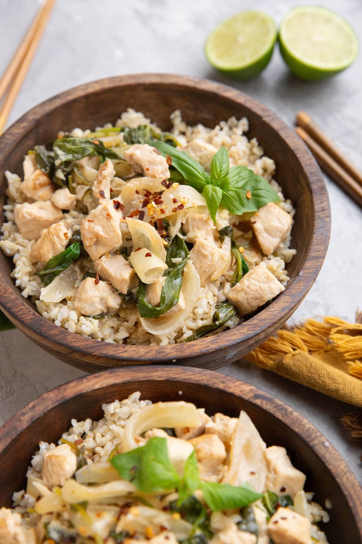 Two wooden bowls of coconut lime chicken and brown rice.