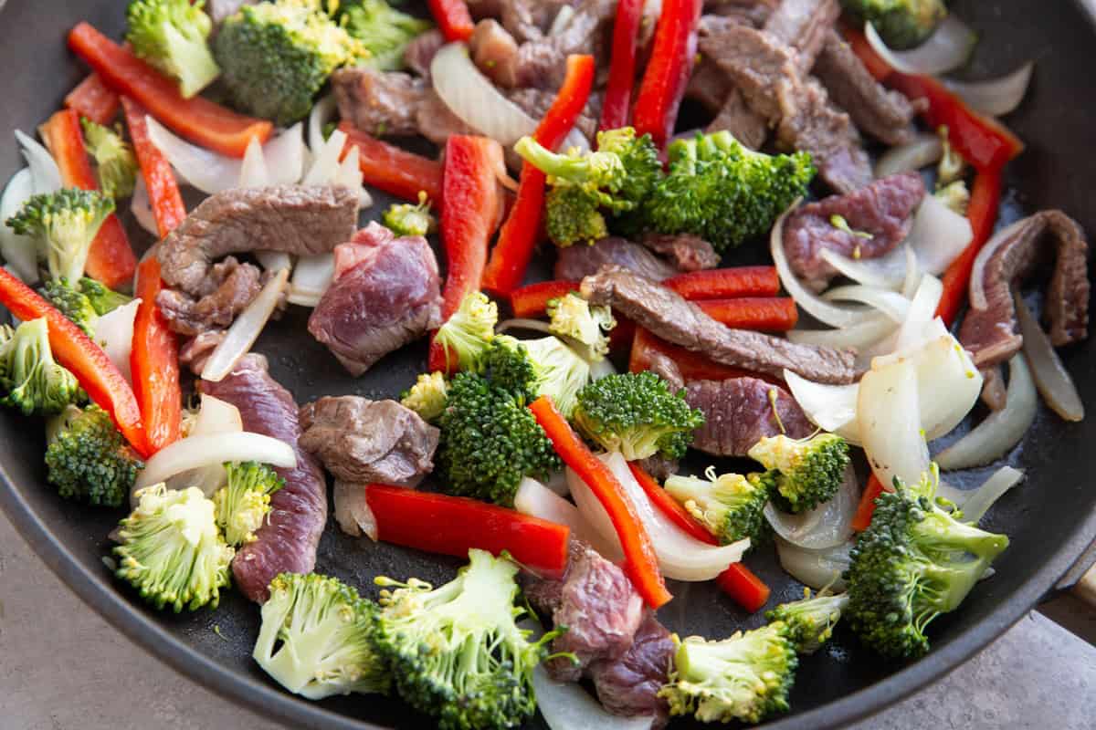 Skillet with beef, onions, broccoli, and bell pepper.