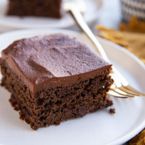 Two slices of black bean chocolate cake on white plates with golden forks, ready to serve.