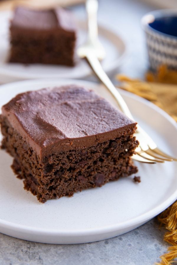 Two slices of black bean chocolate cake on white plates with golden forks, ready to serve.