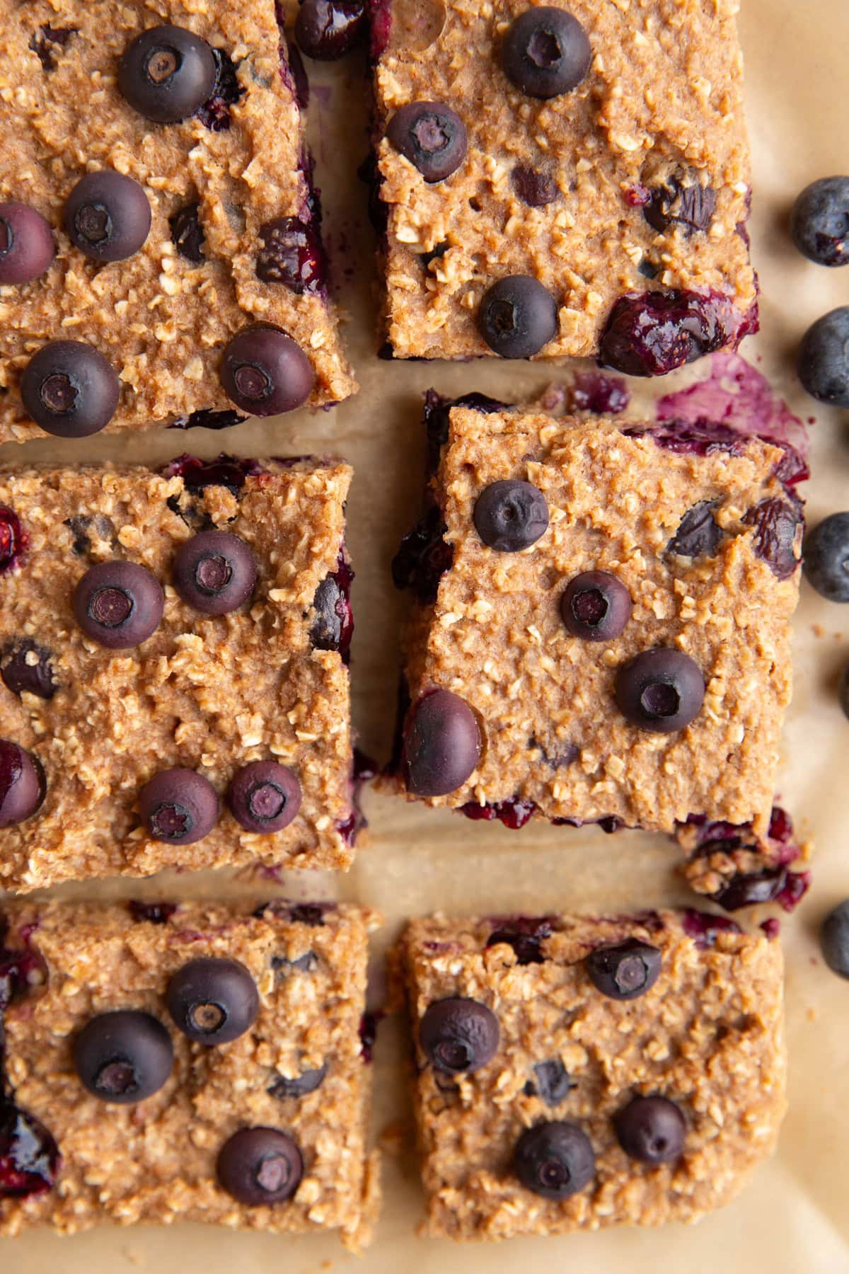 Blueberry Oatmeal Bars on a sheet of parchment paper, cut into slices.