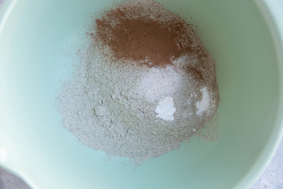 Buckwheat flour, baking powder, salt, and cinnamon in a mixing bowl to make pancakes.