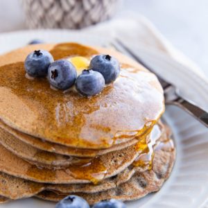 Stack of buckwheat pancakes with blueberries on top.