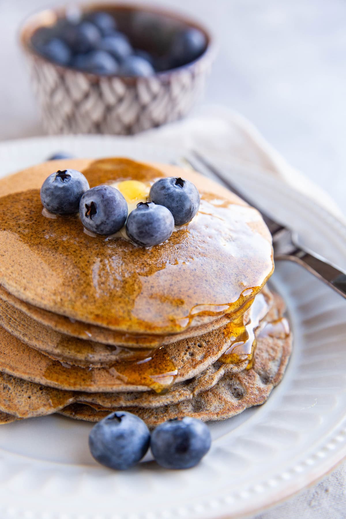 Stack of buckwheat pancakes with blueberries on top.