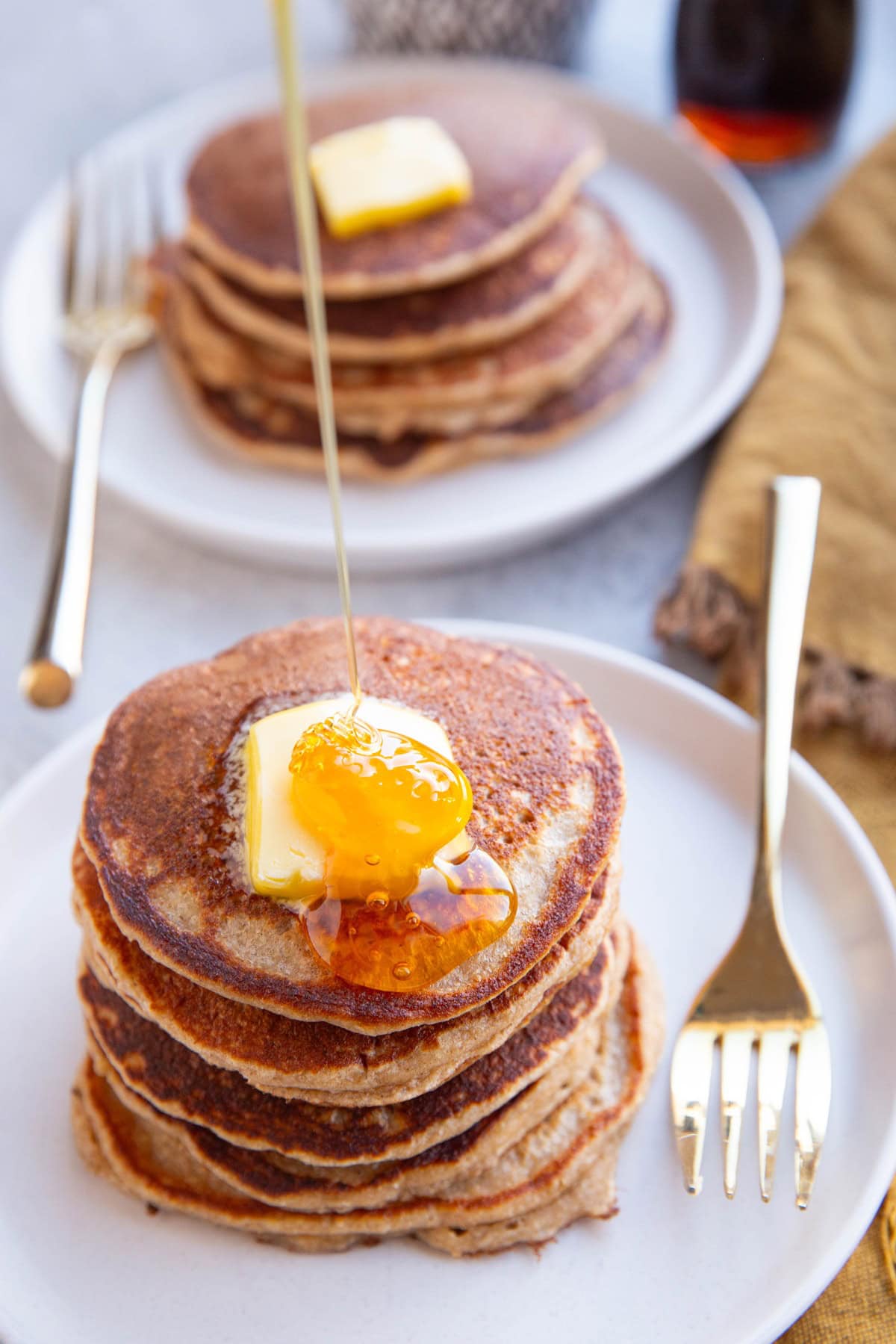 Honey being poured on top of a stack of pancakes for serving.