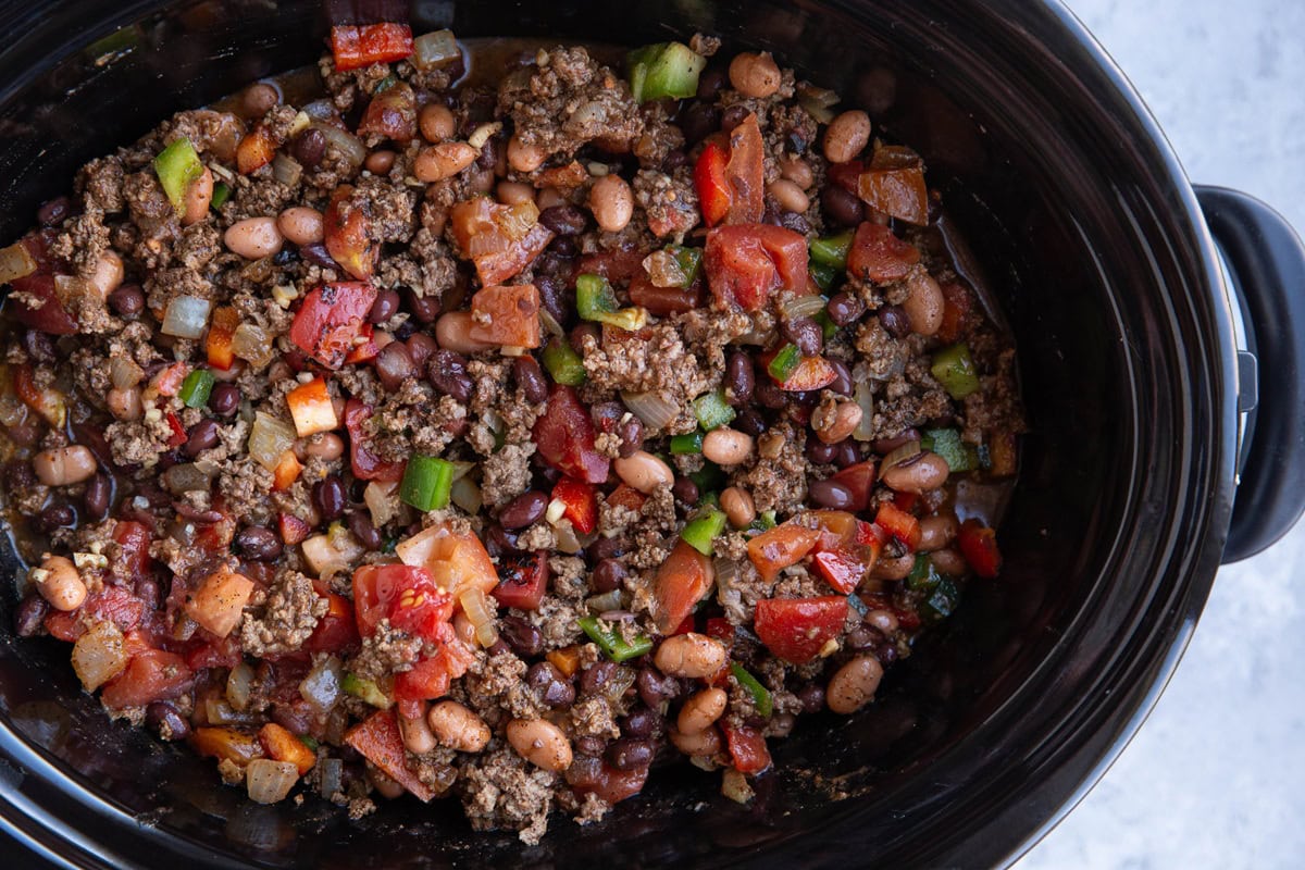 Crock pot full of chili ingredients, ready to be cooked.