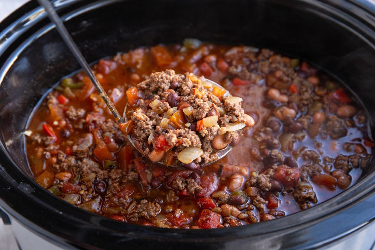 Chili in a crock pot with a ladle scooping some out.