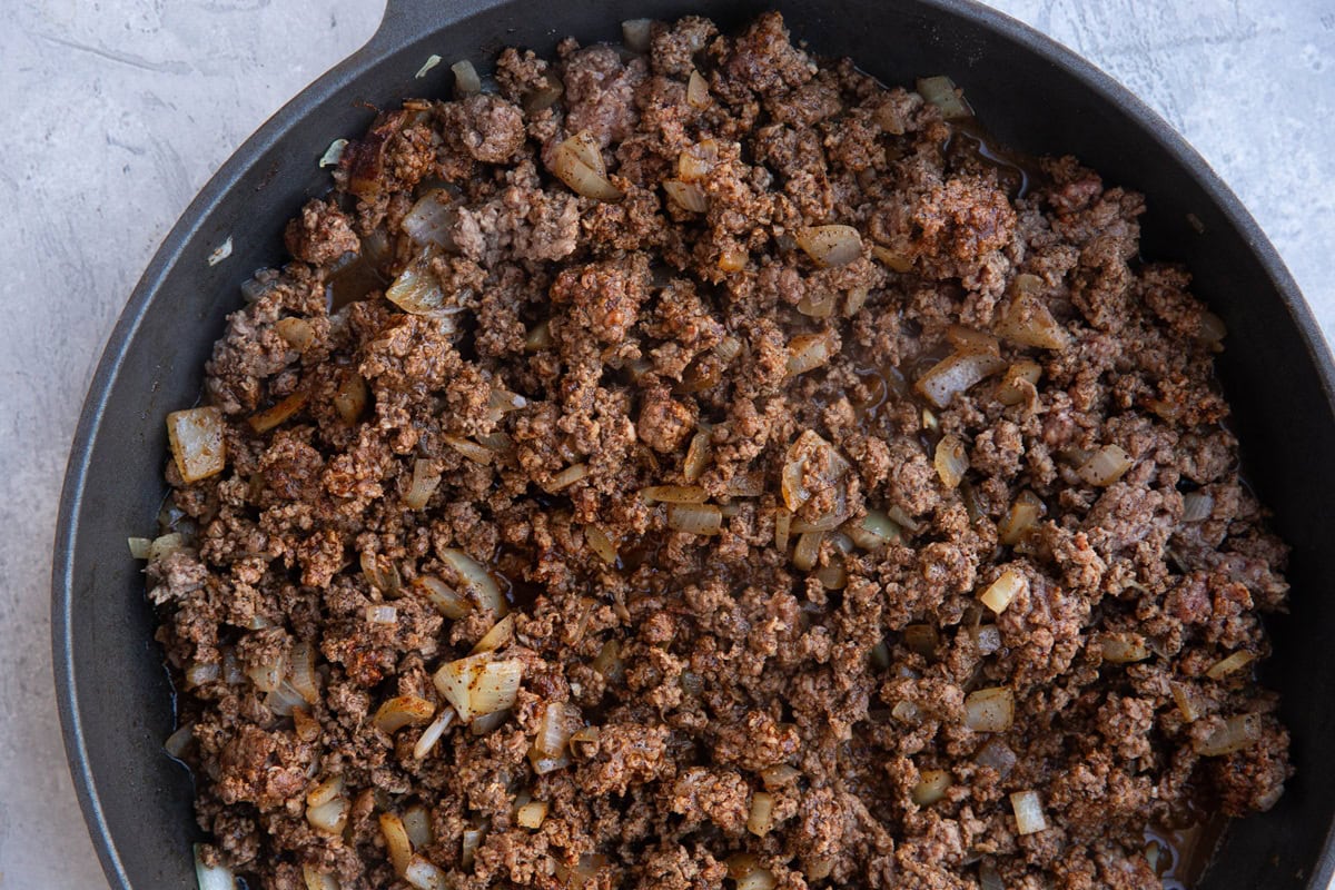 Ground beef and onions cooking in a skillet.