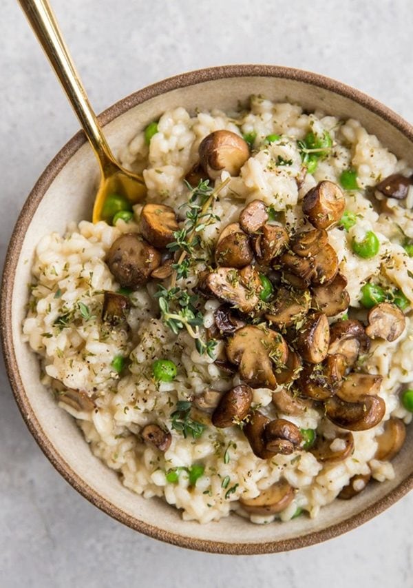 Creamy risotto in a bowl with sauteed mushrooms on top.