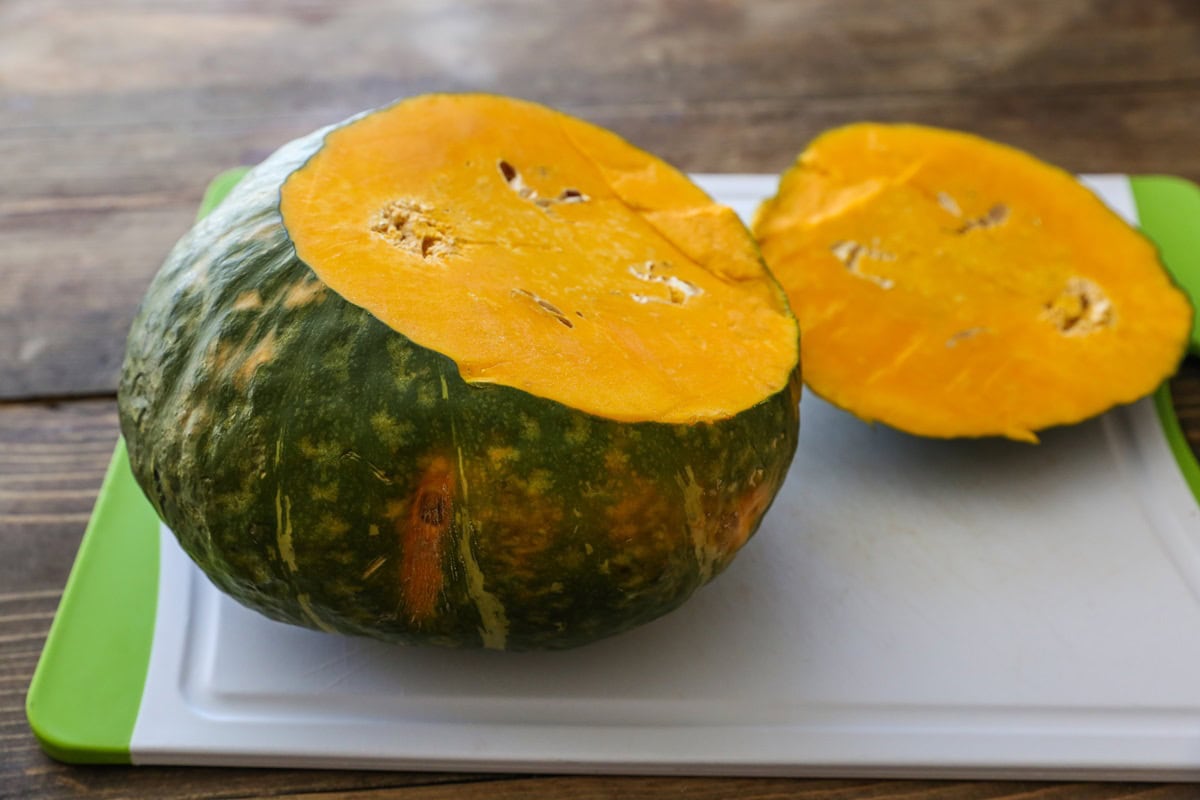 Kabocha squash sitting on a cutting board with the top cut off.