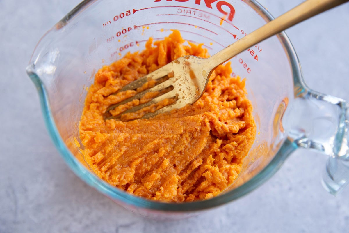 Measuring cup full of mashed sweet potato