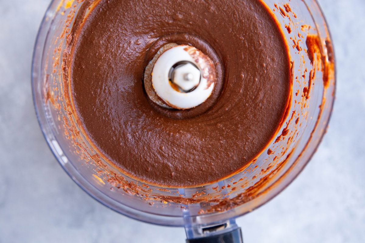 Food processor full of chocolate sweet potato frosting, ready to be used.