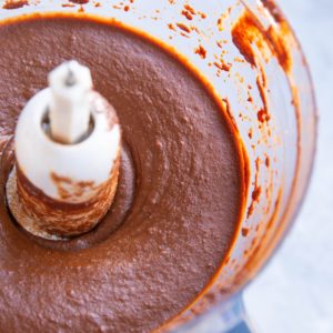 Food processor full of chocolate sweet potato frosting, ready to be used.