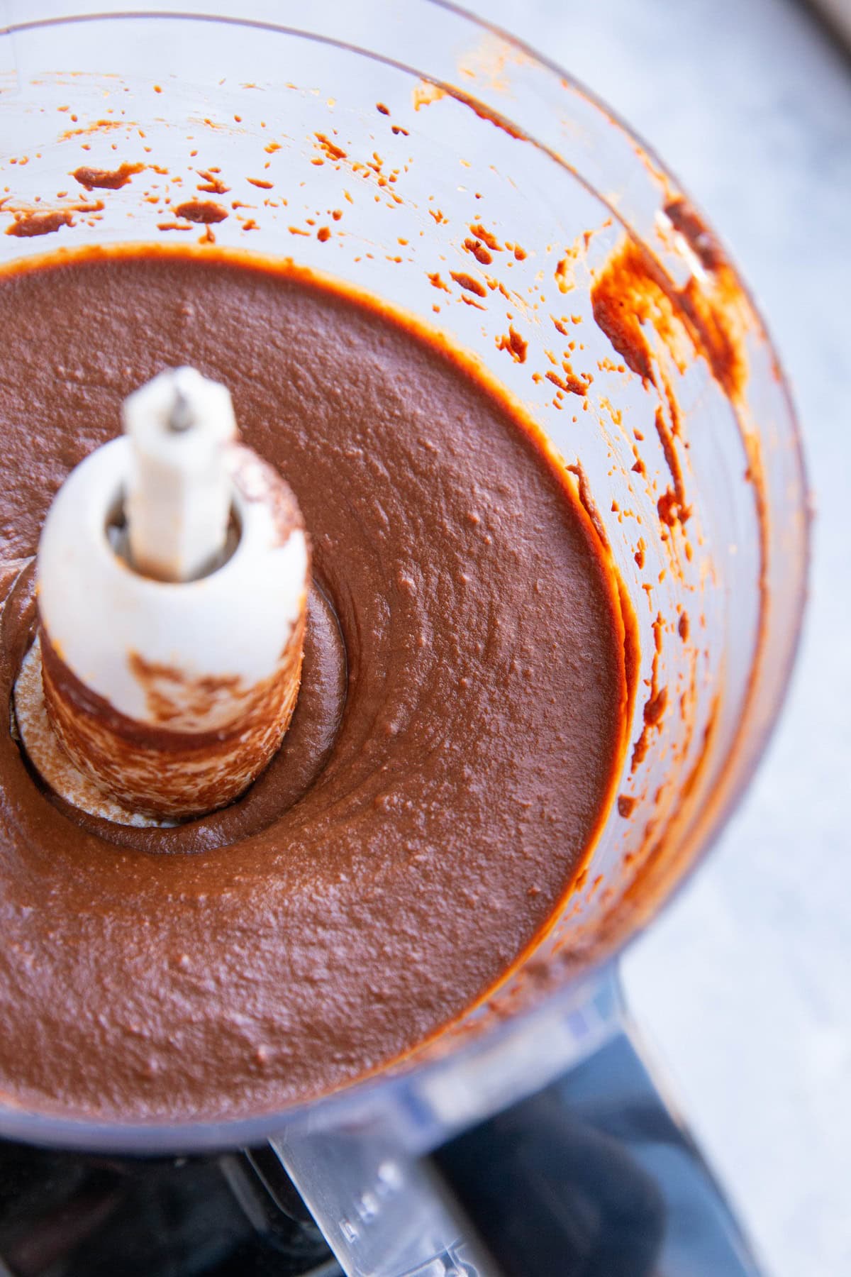 Food processor full of chocolate sweet potato frosting, ready to be used.